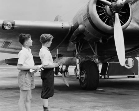 Black and white photo of two young boys looking up at an airplane
